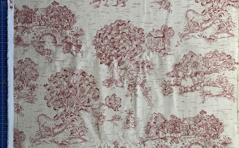 Puede incluir: Una tela de color crema con un patr&oacute;n toile de color rojo oscuro repetitivo. El dise&ntilde;o muestra escenas pastorales con casas, puentes de piedra arqueados, &aacute;rboles grandes, figuras con ropa de &eacute;poca y varios animales como ovejas.