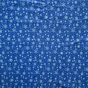 May include: A blue fabric featuring a repeating pattern of white snowflakes in various sizes and intricate designs. The textile displays a dense, scattered arrangement of these winter-themed shapes across the entire surface area.