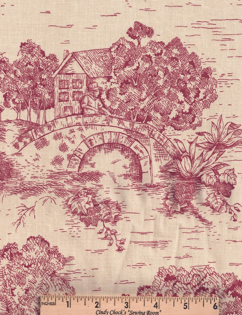 Puede incluir: Una tela beige con un patr&oacute;n toile rojo oscuro de una casa, un puente de piedra y &aacute;rboles. Una regla de madera en la parte inferior muestra una medida de 15,24 cm, con el texto Cindy Chock's Sewing Room impreso.