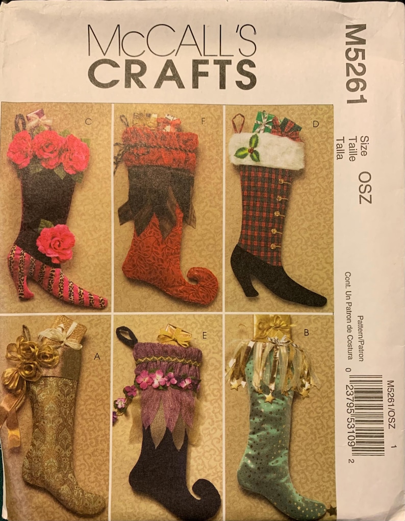 May include: McCall's Crafts M5261 sewing pattern envelope featuring six distinct Christmas stocking designs. The illustrations show various styles including floral, plaid, and metallic fabrics with decorative accents like ribbons, faux fur, and curled toes.