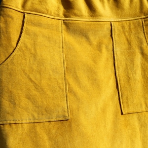 May include: A mustard yellow corduroy skirt with two large patch pockets on the front.