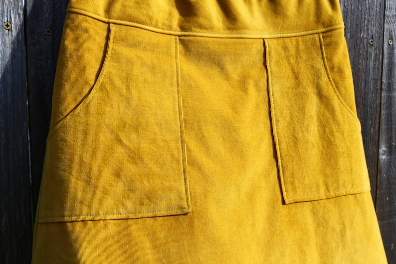 May include: A mustard yellow corduroy skirt with two large patch pockets on the front.