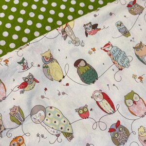 May include: White fabric with a pattern of colorful owls in various poses, connected by curved lines. The owls have different colors and patterns. A section of green fabric with white polka dots is in the upper left corner.
