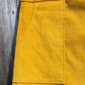 May include: A mustard yellow corduroy skirt with a large patch pocket on the front.