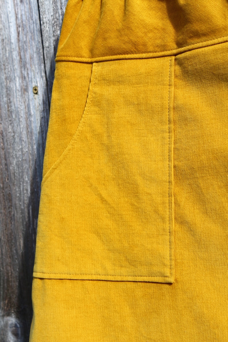 May include: A mustard yellow corduroy skirt with a large patch pocket on the front.