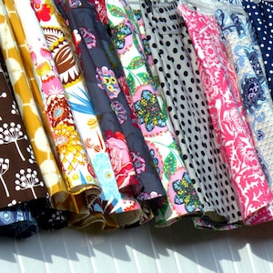 May include: A collection of colorful skirts with various patterns, including floral, polka dots, and abstract designs. The skirts are displayed on hangers, showcasing a variety of fabrics and colors, such as brown, yellow, pink, and blue.
