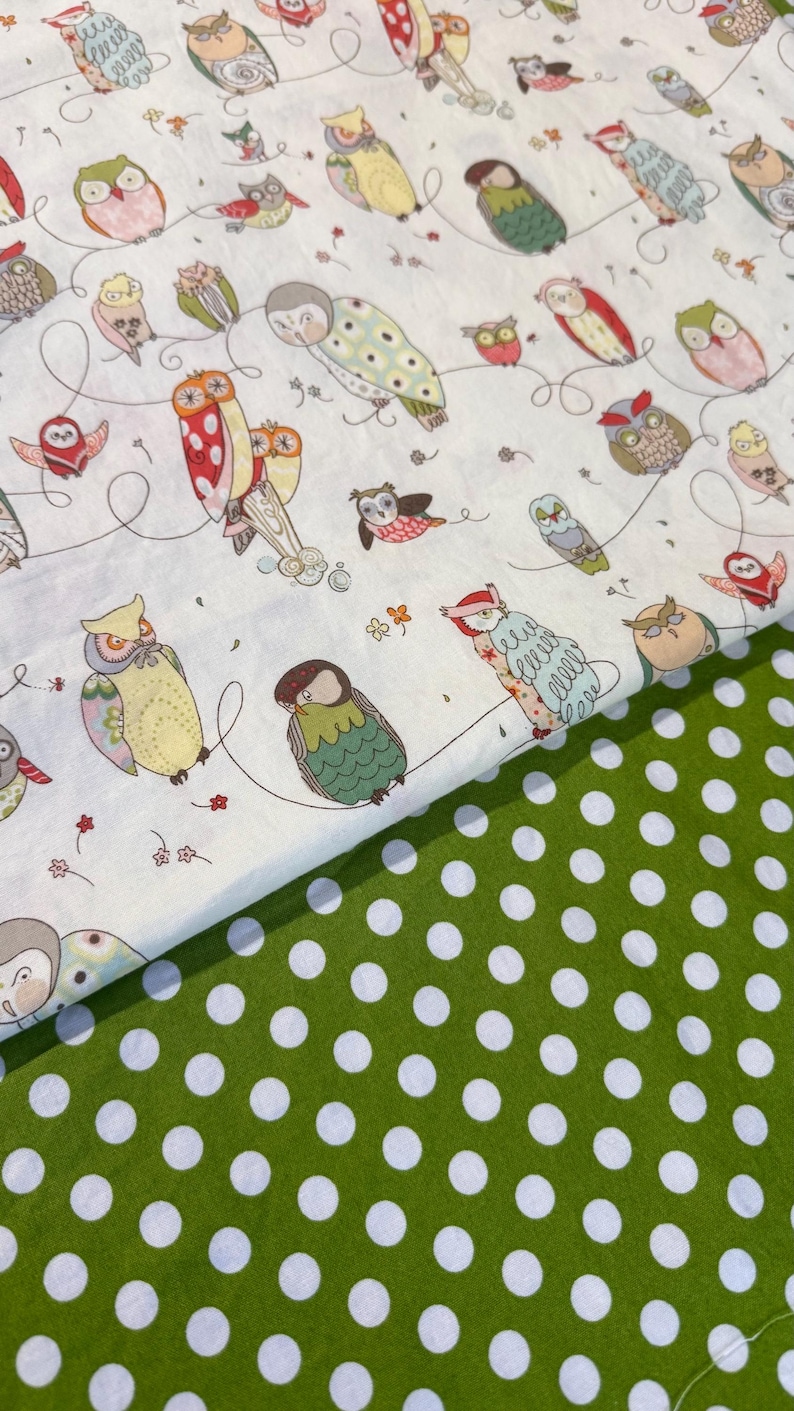 May include: Fabric featuring a whimsical owl pattern on a white background. The owls are in various colors and poses, connected by curved lines. A green fabric with white polka dots is visible below the owl fabric.