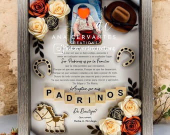 May include: A framed shadow box with a white background and a photo of a baby boy. The box is decorated with paper flowers, a wooden horseshoe, a wooden horse, and wooden blocks that spell out "Padrinos". The text in the box reads "Ser Padrinos es ser la Familia que la vida permite que escojamos." and "De Bautigo? Con amor Mateo A. Mendoza".