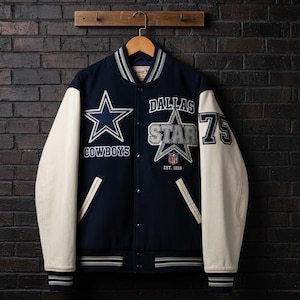 Puede incluir: Chaqueta universitaria azul marino y crema con el logotipo de los Dallas Cowboys y el texto "DALLAS STAR". La chaqueta presenta un gran emblema de estrella, el número 75 y el logotipo de la NFL. Las mangas son de color crema y la chaqueta está colgada en una percha de madera.