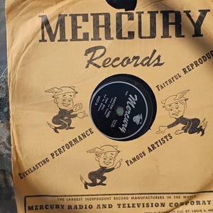 Può includere: Un disco in vinile Mercury Records da 7 pollici vintage nella sua custodia di carta marrone originale. La custodia presenta il logo Mercury Records, personaggi dei cartoni animati e testo. L'etichetta del disco è in bianco e nero.