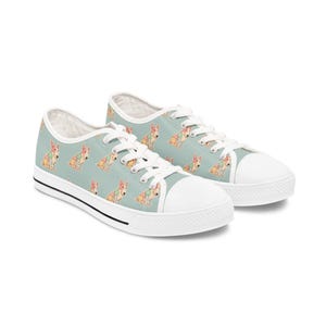 May include: Canvas sneakers featuring a light blue background adorned with a repeating pattern of cartoon dogs. The shoes have white laces, a white toe cap, and a black stripe along the sole.