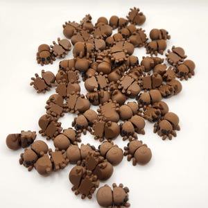 May include: A large group of brown, plastic, spider-shaped figurines. The spiders have eight legs and black eyes.