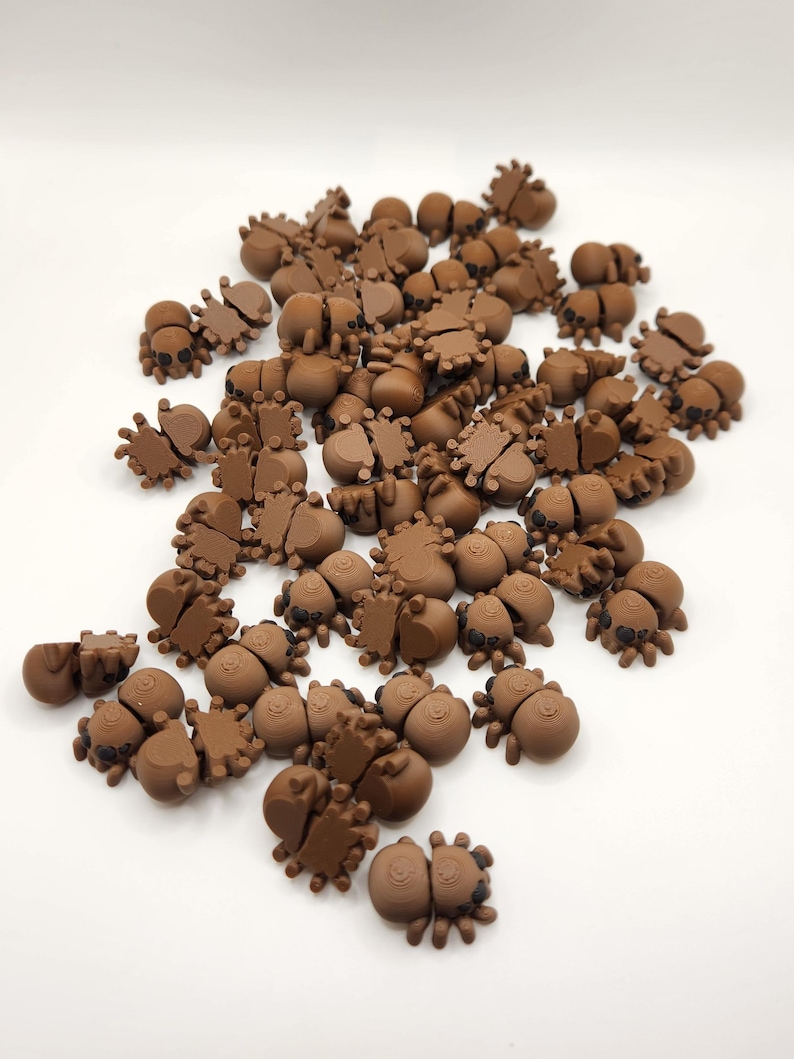 May include: A large group of brown, plastic, spider-shaped figurines. The spiders have eight legs and black eyes.
