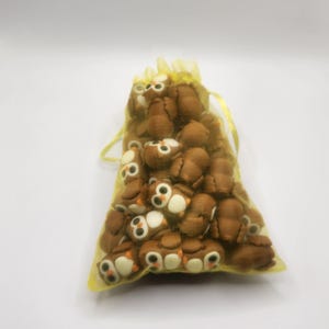 May include: A yellow organza bag filled with brown owl-shaped erasers.