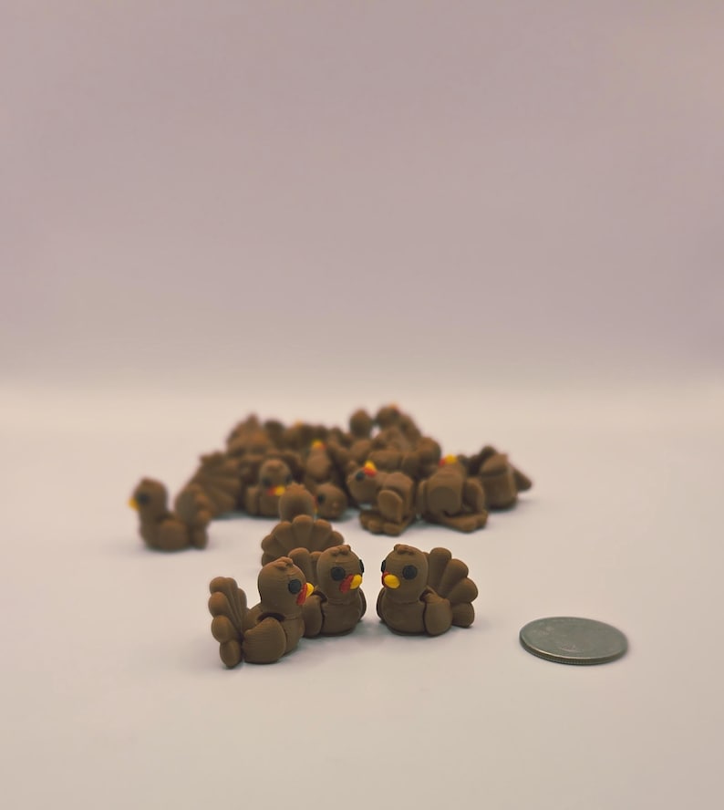 May include: A group of small, brown turkey figurines with yellow beaks and red snoods. The turkeys are clustered together, with a few in the foreground and many more in the background. A coin is next to the turkeys.