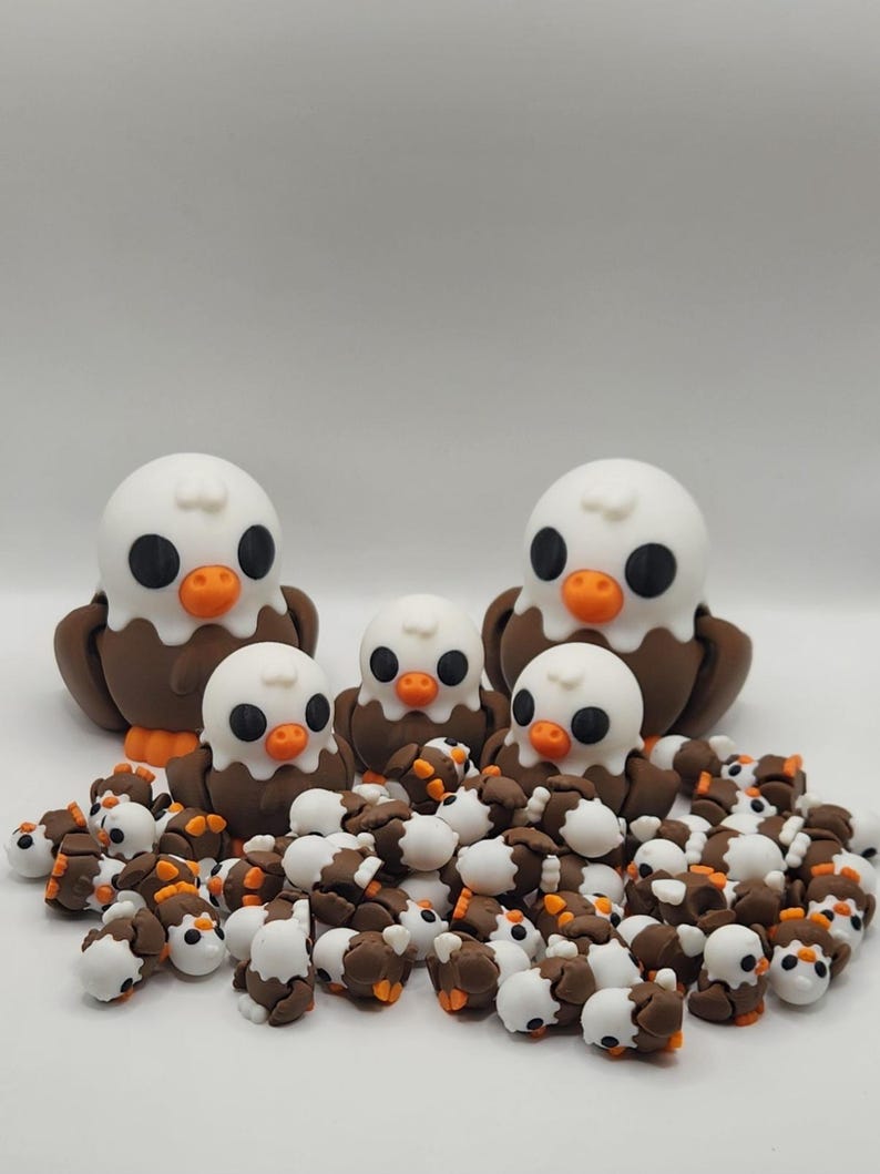 May include: A group of brown and white ceramic eagle figurines. There are three larger eagles and many smaller ones. The larger eagles have orange beaks and black eyes. The smaller eagles have brown beaks and black eyes.