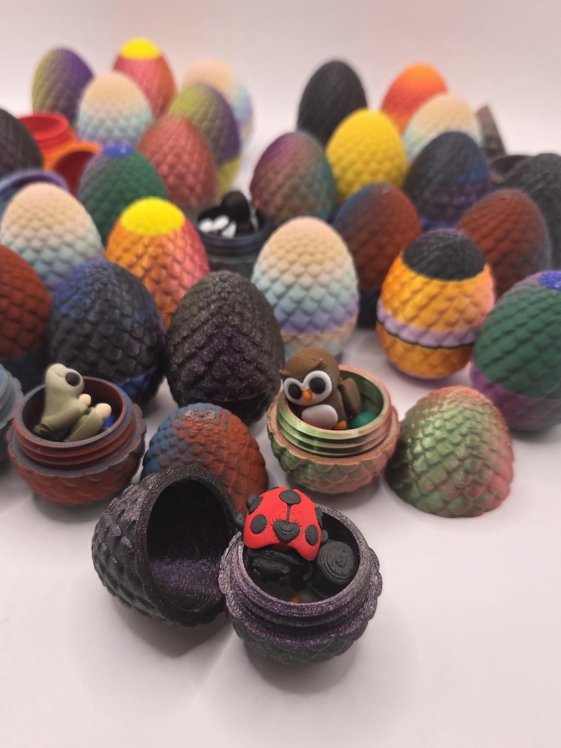 May include: A collection of colorful, dragon egg-shaped containers, some open to reveal small figurines like an owl and a ladybug. The eggs vary in color, including shades of blue, green, yellow, and orange, with textured surfaces.