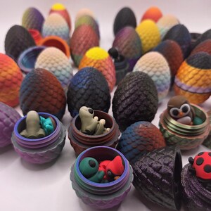 May include: A collection of colorful, textured egg-shaped objects, some with open containers revealing small figurines. The eggs display a variety of colors, including orange, yellow, blue, and purple. Some containers hold small creatures.