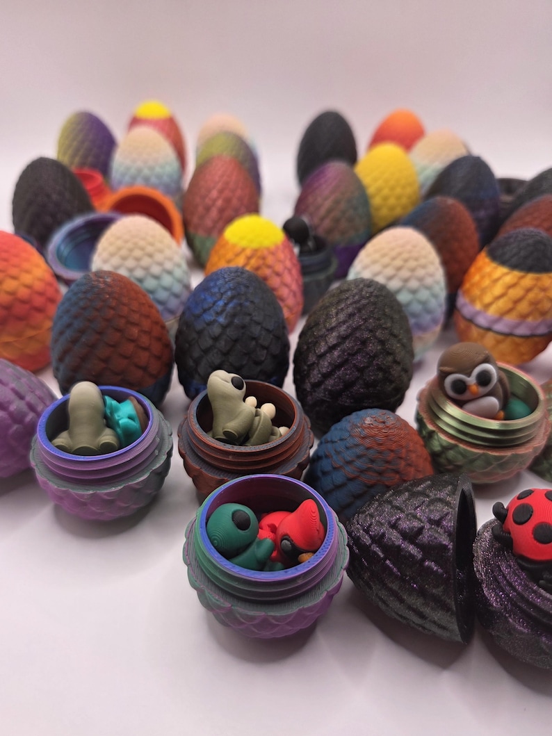 May include: A collection of colorful, textured egg-shaped objects, some with open containers revealing small figurines. The eggs display a variety of colors, including orange, yellow, blue, and purple. Some containers hold small creatures.