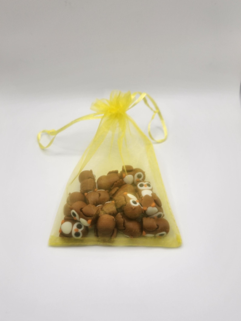 May include: A yellow organza bag filled with small brown owl-shaped erasers.