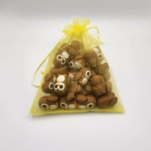 May include: A yellow organza bag filled with brown owl-shaped erasers.