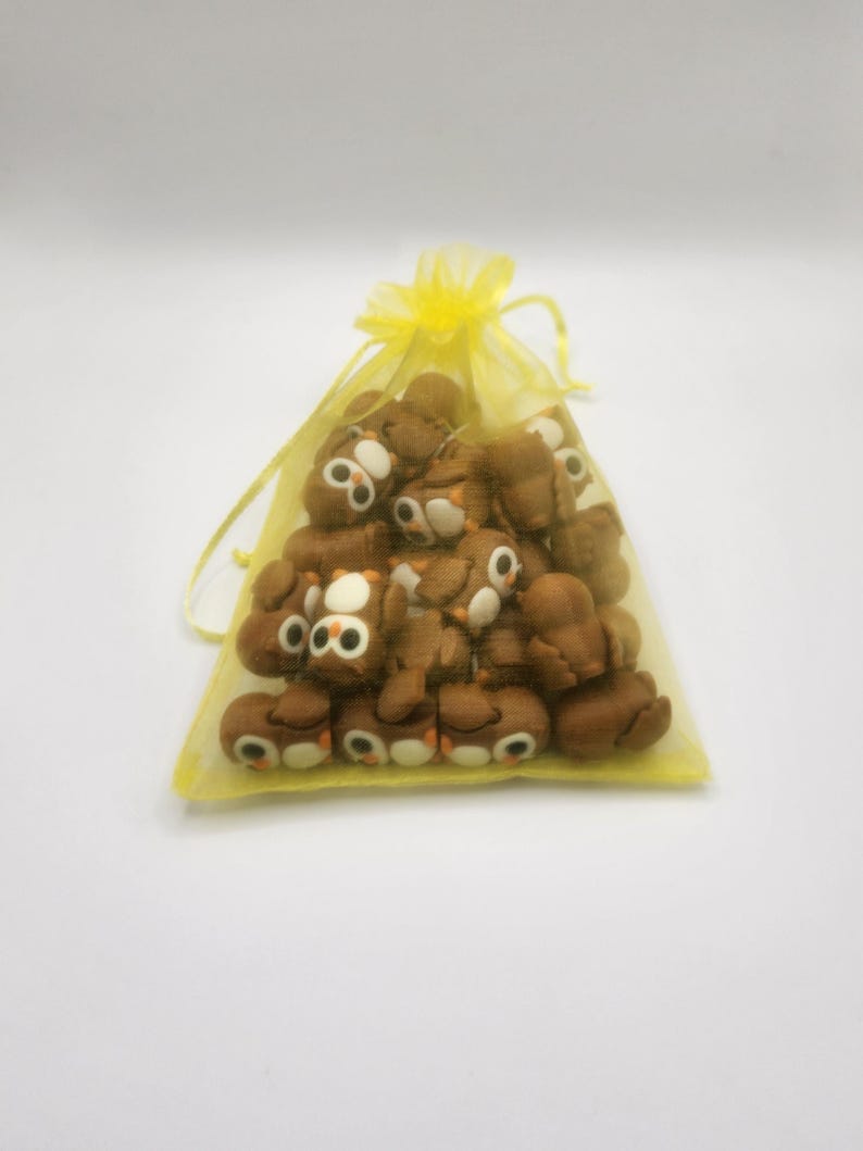 May include: A yellow organza bag filled with brown owl-shaped erasers.