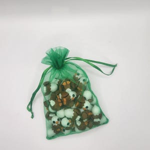 May include: A green mesh bag filled with small, brown and white ceramic penguin figurines.