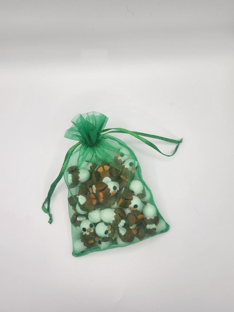 May include: A green mesh bag filled with small, brown and white ceramic penguin figurines.