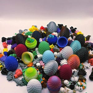 May include: A collection of colorful, textured dragon eggs in various sizes and hues, including blue, green, red, and silver. The eggs are mixed with small figurines of creatures and skulls, creating a fantasy theme.