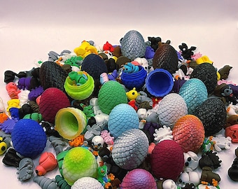 May include: A pile of colourful dragon eggs with textured surfaces in shades of blue, green, red, and silver. The eggs are mixed with small figurines of creatures and skulls, creating a fantasy theme.