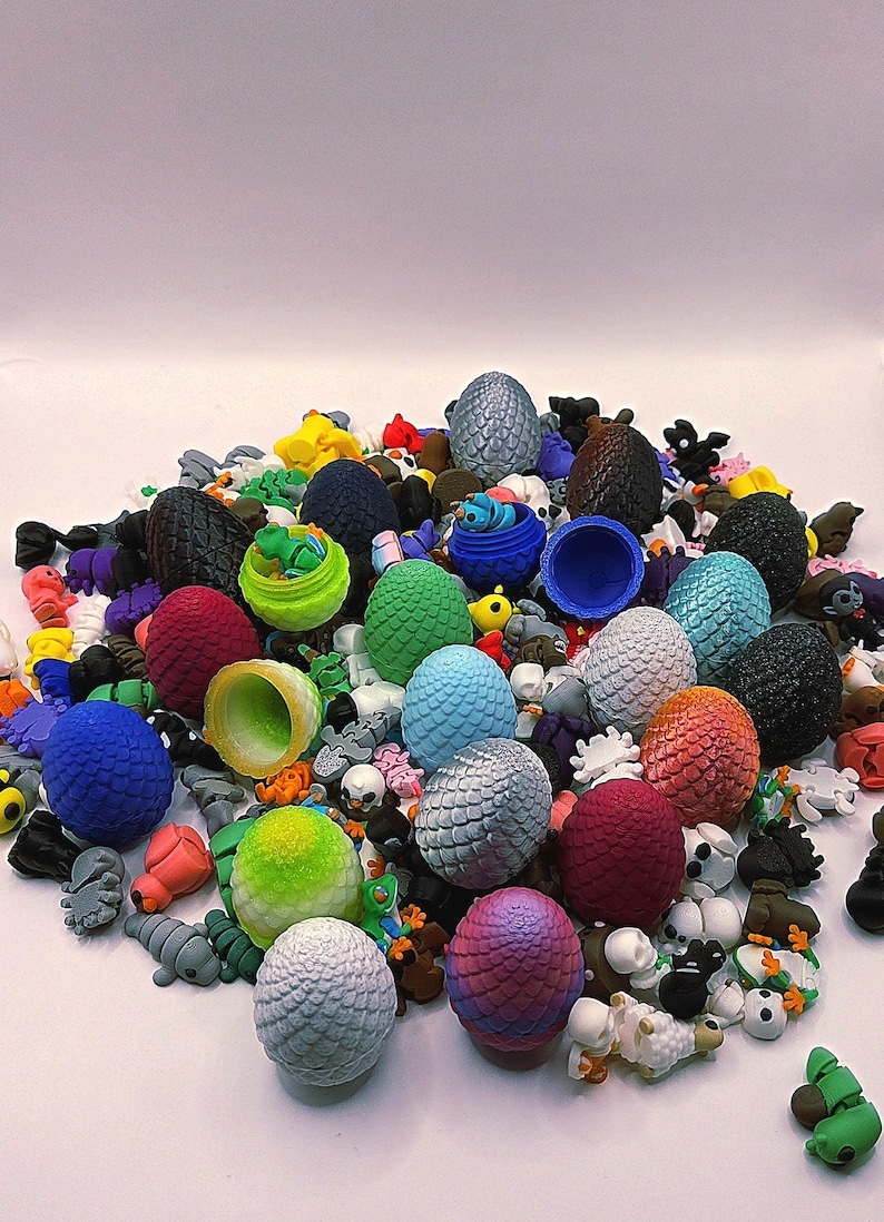 May include: A collection of colorful, textured dragon eggs in various sizes and hues, including blue, green, red, and silver. The eggs are mixed with small figurines of creatures and skulls, creating a fantasy theme.