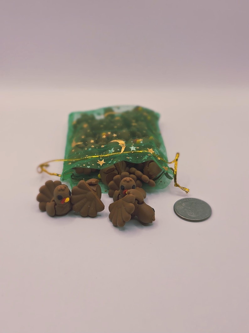 May include: Small, brown turkey figurines with orange beaks and red wattles, scattered near a green mesh bag with gold detailing. A UK coin is next to the turkeys.