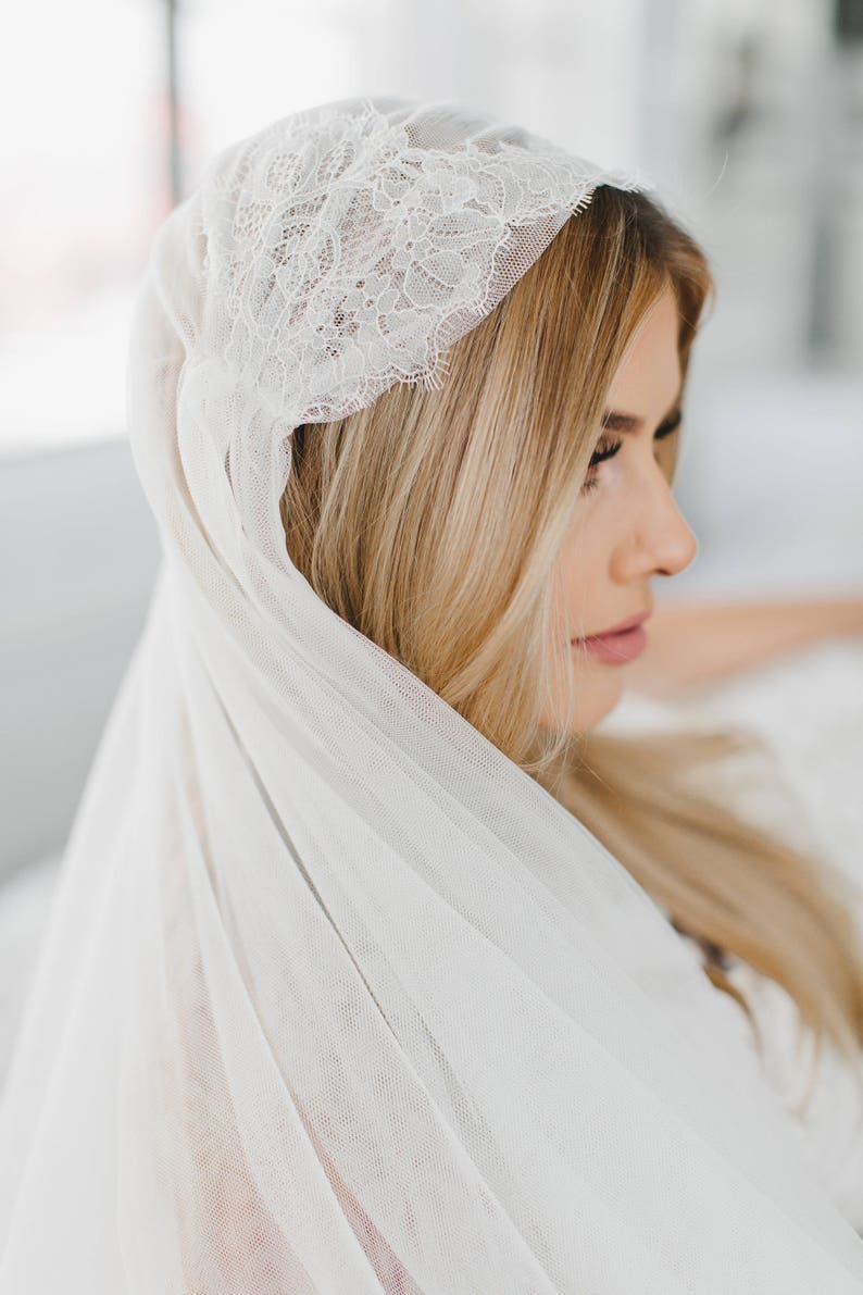 May include: A white bridal veil with a delicate lace trim. The veil is made of soft tulle and is perfect for a wedding ceremony.