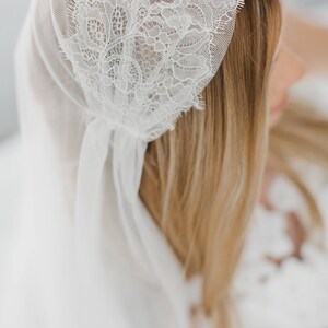 May include: A white bridal veil with delicate lace trim. The veil is made of soft, sheer fabric and is perfect for a wedding or special occasion.