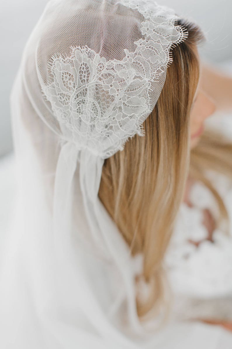 May include: A white bridal veil with delicate lace trim. The veil is made of soft, sheer fabric and is perfect for a wedding or special occasion.