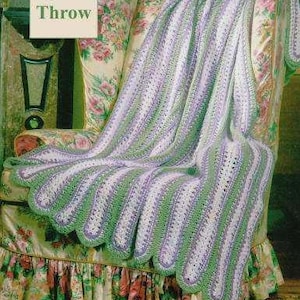 May include: A crocheted throw blanket in shades of green and purple with a scalloped edge. The blanket is draped over a floral patterned armchair. The text "Quick Throw" is visible in the upper left corner of the image.