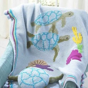 May include: A crocheted baby blanket with a blue background and a sea turtle design. The blanket has a colorful border and a 3D crocheted sea turtle in the foreground.