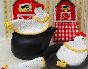 May include: Set of three crocheted chicken pot holders. The pot holders are white with yellow accents and feature a red and white barn design. The pot holders are displayed on a black cast iron teapot and skillet.