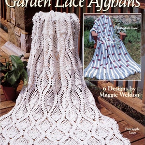 May include: A book cover featuring a white crocheted afghan with tassels. The title of the book is "Garden Lace Afghans" and the subtitle is "6 Designs by Maggie Weldon".