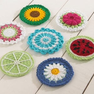 May include: Seven crocheted coasters featuring various fruit and flower designs. The coasters are made in a variety of colors, including green, red, white, blue, and yellow.