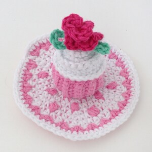 May include: A pink and white crocheted hat with a pink flower on top. The hat is made with a delicate stitch pattern and has a wide brim.