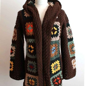 May include: A brown crocheted cardigan with a hood, featuring a patchwork design of colorful squares. The cardigan has a long, open front and long sleeves.