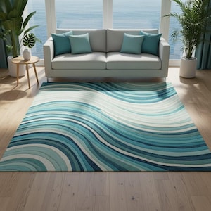 Op de afbeelding: Een rechthoekig vloerkleed met een golvend patroon in blauw- en wittinten. Het kleed ligt op een houten vloer voor een grijze bank met turquoise kussens. De achtergrond toont een groot raam met uitzicht op de zee.