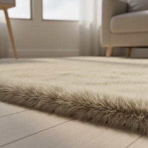 May include: Close-up of a beige faux fur rug with long, soft fibers. The rug is placed on a light-colored wooden floor, with a glimpse of a window and a beige armchair in the background. The rug adds a touch of warmth and texture to the room.