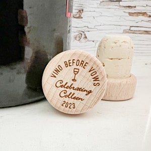 Wooden bottle stopper with the text "Vino Before Vows Celebrating Colleen 2023" and a wine glass icon.