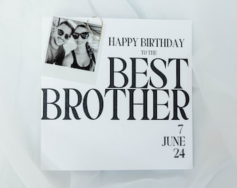 May include: A white greeting card with the text "HAPPY BIRTHDAY TO THE BEST BROTHER" in bold black font. A small black and white photo is attached with twine. The date "7 JUNE 24" is printed below.