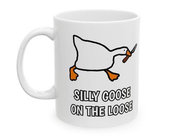 Könnte beinhalten: Weiße Keramiktasse mit einer Cartoon-Gans, die ein Messer hält, und dem Text "Silly Goose on the Loose".