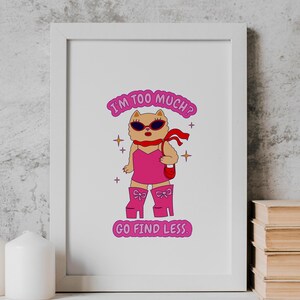 Puede incluir: Una impresi&oacute;n enmarcada en blanco con un gato de dibujos animados rosa que lleva gafas de sol y un vestido rosa. El texto de la impresi&oacute;n dice "&iquest;Soy demasiado? Ve a buscar menos."