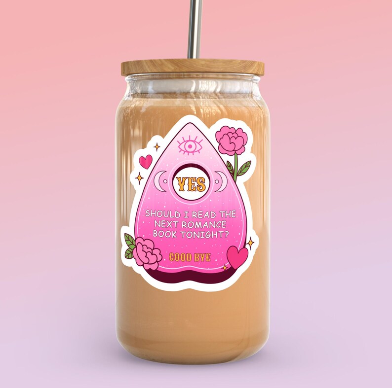 Op de afbeelding: Een roze en witte sticker met een Ouija-bordontwerp op een glazen pot met een bruin deksel. De sticker zegt "JA" en "Moet ik vanavond het volgende romanboek lezen? Tot ziens".