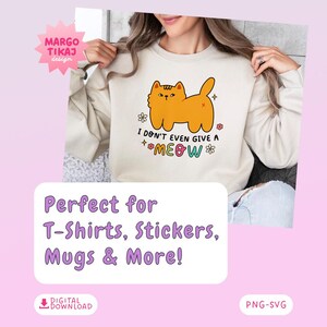 以下が含まれることがあります： 白いスウェットシャツに、オレンジ色の猫の漫画と「I don't even give a meow」というカラフルな文字が書かれています。テキストは小さな花で囲まれています。